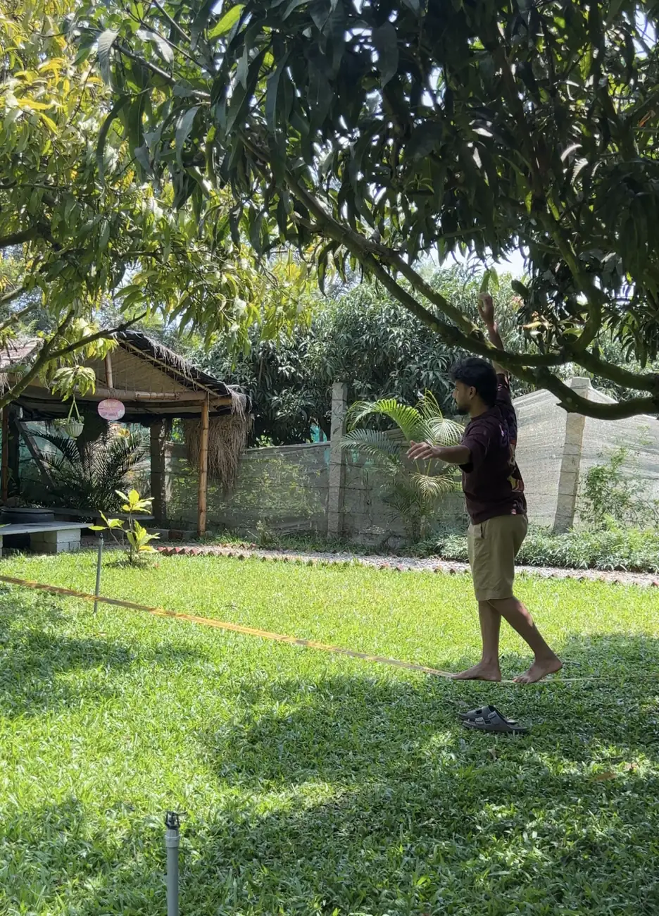 A guest walking a slackline barefoot on the lawn.